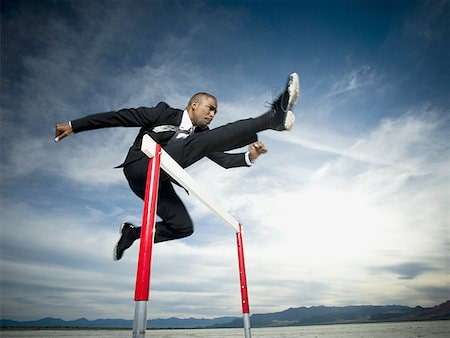business man jumping over hurdles